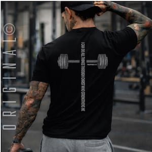a person wearing a black t-shirt with a graphic design on the back, including a barbell and text.