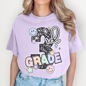 a girl wearing a purple shirt that says 5th grade