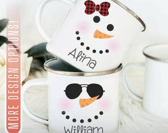 May include: Two white enamel mugs stacked, each with a snowman face design. One has a red and black plaid bow, the other sunglasses. The top mug says "Alina", the bottom says "William".