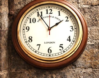 Reloj de pared londinense antiguo con marco de madera rústica y acabado en latón.