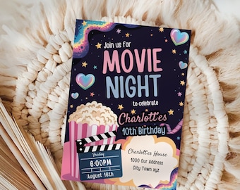 以下が含まれることがあります： 映画の夜の招待状。濃い青色の背景に、ピンクと青で「MOVIE NIGHT」の文字。ポップコーン、映画の小道具、そして「Charlotte's 10th Birthday」の文字が含まれています。日付と時間も記載されています。