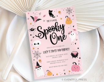 May include: A pink Halloween-themed birthday invitation with the text "She's a Real Spooky One." The invitation features illustrations of a black cat, bat, spider, skull, ghost, pumpkin, and candy corn. It's for Lucy's first birthday, on October 28th.
