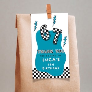 May include: A gift tag with the number 67 in a checkered pattern, teal accents, and lightning bolt graphics. The tag reads "Thank You for coming to Luca's 7th Birthday" in a playful font. The tag is attached to a brown paper bag.