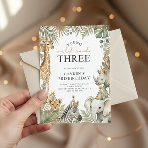 Könnte beinhalten: Eine Geburtstagseinladung mit Dschungel-Thema. Die Einladung zeigt eine Giraffe, einen Löwen, ein Zebra, einen Elefanten, ein Nashorn und einen Affen mit Partyhüten. Der Text lautet "Young, wild and THREE" und enthält Party-Details.