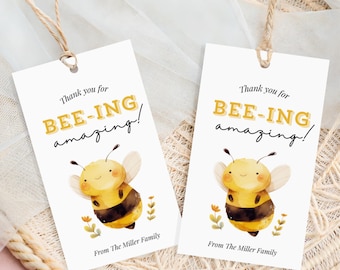 May include: Two white gift tags with the text "Thank you for BEE-ING amazing!" in yellow and black. Each tag features a watercolor illustration of a smiling bee. The tags are tied with twine.