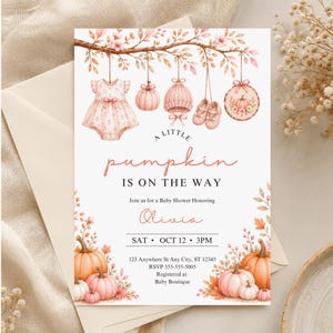 Puede incluir: Una tarjeta de invitación para baby shower con ilustraciones en acuarela de un vestido de bebé, calabaza, gorro de punto, patucos y bastidor de bordado colgando de una rama. Texto: A LITTLE pumpkin IS ON THE WAY, Olivia, SAT OCT 12 3PM.