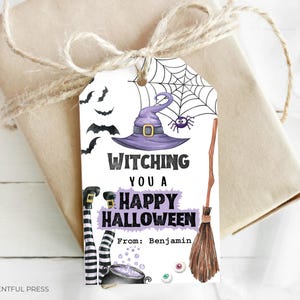 May include: A Halloween gift tag with a witch theme. The tag features a purple witch hat, spider web, bats, and the text "Witching You a Happy Halloween." A broom, witch legs, and cauldron are also depicted. The tag is tied to a wrapped gift.
