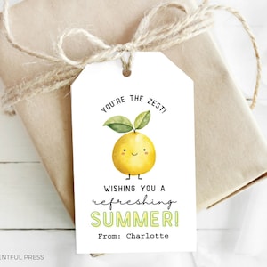 Può includere: Un'etichetta regalo bianca con un'illustrazione di limone giallo e il testo "You're the zest! Wishing you a refreshing summer! From: Charlotte".
