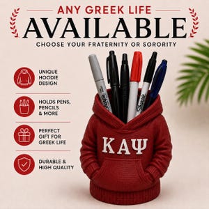 Op de afbeelding: Een bordeauxrode bureau-organizer in de vorm van een miniatuur hoodie met de Griekse letters KΑΨ in het wit op de voorkant. De hoodie heeft een capuchon, lange mouwen en een voorzak, en is gevuld met diverse pennen en markers.