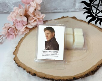 May include: A clear plastic package containing six square wax melts and a card with a photo of Dean Winchester. The card reads "DEAN WINCHESTER" and "ALL NATURAL SOY WAX MELT 2.5 oz HAND POURED IN ALGONQUIN, IL".