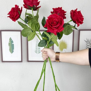 Könnte beinhalten: Ein Strauß aus fünf künstlichen roten Rosen mit grünen Blättern und Stielen.