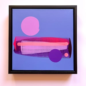 May include: A square framed painting on a periwinkle blue background featuring a large light pink circle, a smaller dark purple circle, and a tiny light pink dot. A central horizontal rectangular shape displays layered shades of magenta and pink.