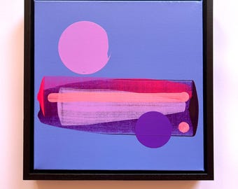 Puede incluir: Una pintura cuadrada enmarcada sobre un fondo azul bígaro que presenta un círculo grande de color rosa claro, un círculo más pequeño de color morado oscuro y un punto diminuto de color rosa claro. Una forma rectangular horizontal central muestra tonos superpuestos de magenta y rosa.