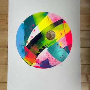 May include: Abstract art print with a vibrant, colourful design. A circular composition with bold brushstrokes in blue, green, yellow, pink, and gold. The artwork is on a white paper background.