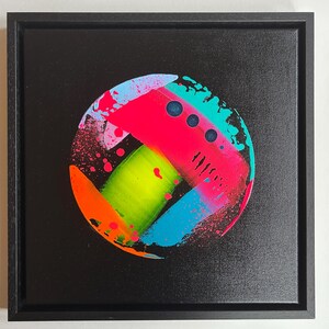 Pode incluir: Uma tela quadrada emoldurada apresentando uma pintura abstrata circular sobre um fundo preto. O design inclui pinceladas neon vibrantes em rosa, verde-lim&atilde;o, azul brilhante e laranja com efeitos de respingos e tr&ecirc;s pontos circulares azul-escuro.