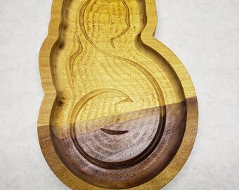 May include: A wooden tray carved in the shape of a woman with a baby. The tray is made of two tones of wood, with a light brown top half and a darker brown bottom half. The design features a silhouette of a mother and child.