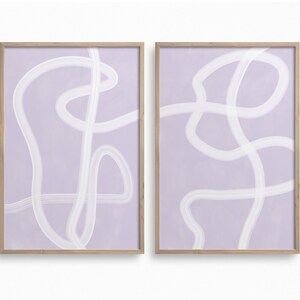 May include: Two framed abstract art prints with a light purple background and white abstract lines. The prints are in wooden frames.
