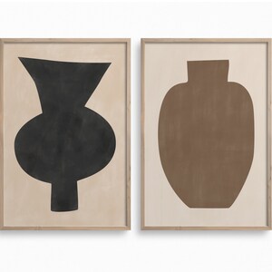 May include: Two framed prints of abstract vase shapes. The left print features a black vase with a rounded body and a narrow neck. The right print features a brown vase with a rounded body and a wide neck.