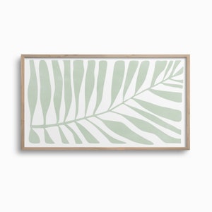 Op de afbeelding: Een ingelijste print van een gestileerd groen blad op een witte achtergrond. Het blad is een eenvoudig ontwerp met een enkele stengel en meerdere takken.