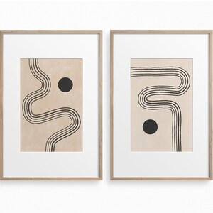 Puede incluir: Dos impresiones enmarcadas con arte de l&iacute;neas abstractas y c&iacute;rculos negros sobre un fondo beige. Las impresiones est&aacute;n en marcos de madera simples.