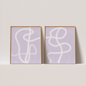May include: Two framed abstract art prints with white lines on a light purple background.