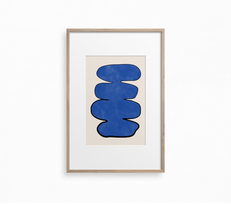 May include: A framed abstract print with a blue, organic shape resembling a stack of stones on a cream background.