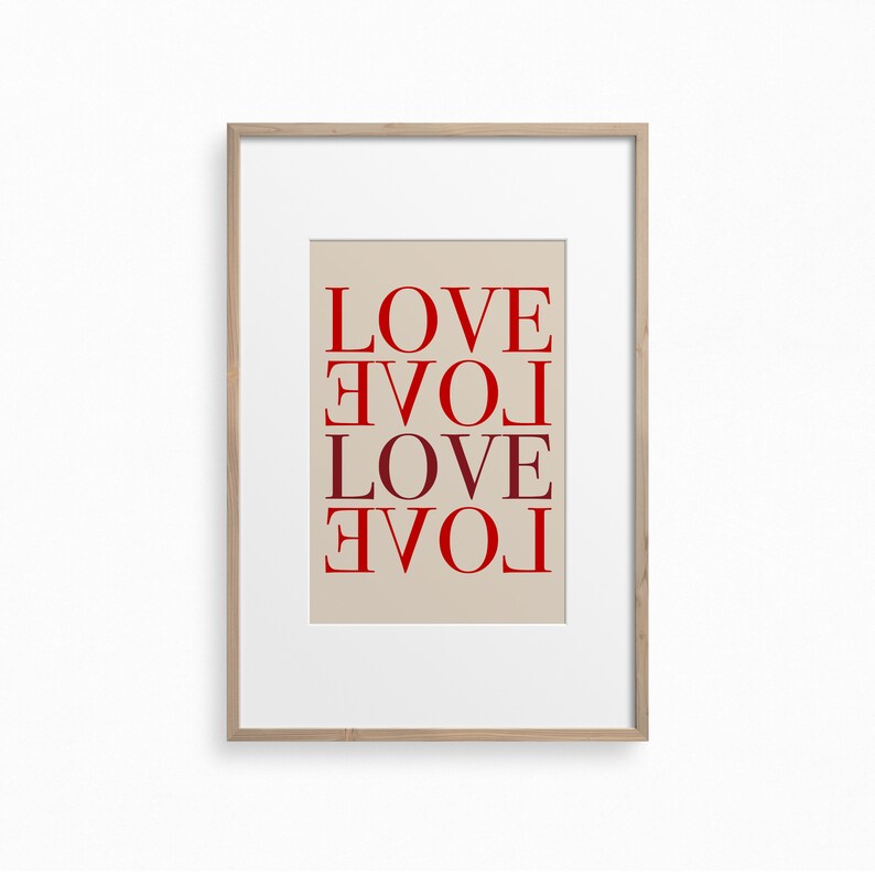 May include: A framed print with the word "LOVE" repeated four times in a vertical column, with each word rotated 90 degrees clockwise from the one above it. The words are in a red color on a beige background.