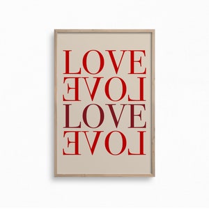 May include: A framed print with the word "LOVE" repeated four times, each time rotated 90 degrees clockwise. The background is a light beige color and the text is in red.
