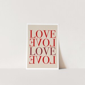 May include: A beige card with the word "LOVE" repeated four times in red and burgundy lettering. The word is flipped upside down in the second and fourth instances.