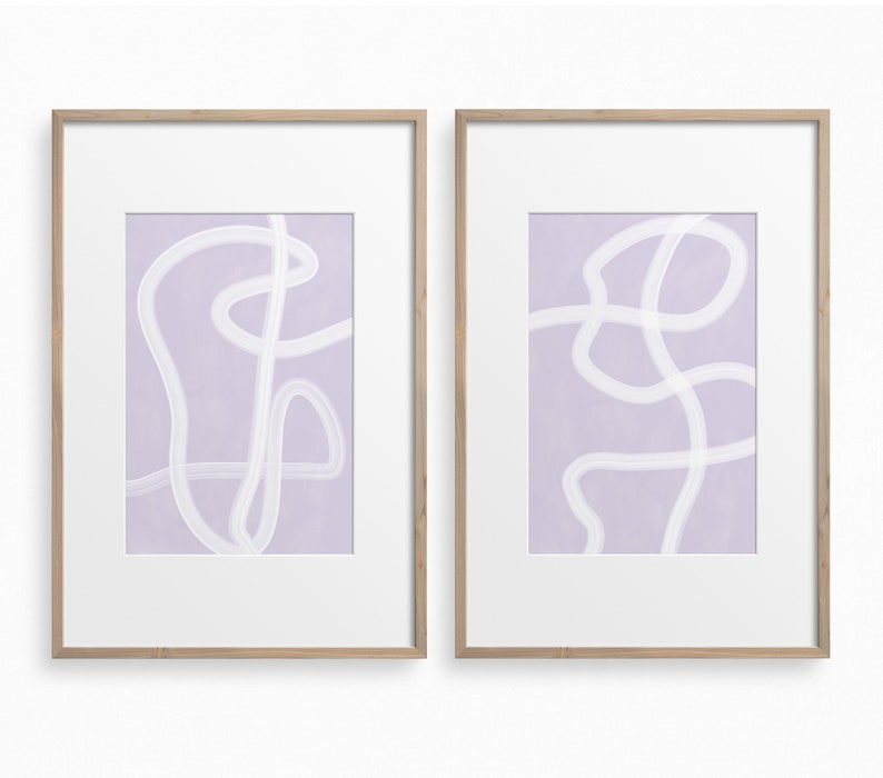 May include: Two framed abstract art prints with a light purple background and white lines. The prints are in simple wooden frames.