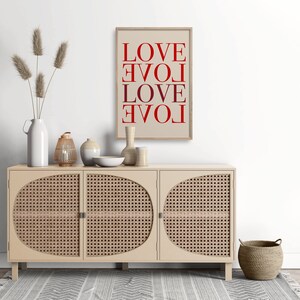 May include: A beige cabinet with three doors and woven cane panels. The cabinet is decorated with a framed print that reads "LOVE LOVE LOVE LOVE" in red lettering. The print is on a beige background.