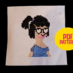Puede incluir: Patrón de punto de cruz que presenta un personaje de dibujos animados con cabello negro, gafas y una parte superior azul. El diseño está sobre un fondo de tela blanca. Un círculo amarillo con "PDF PATTERN" está en la esquina.