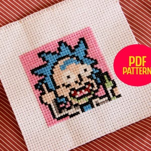 Può includere: Uno schema di punto croce di un personaggio dei cartoni animati con i capelli blu e uno sfondo rosa. Lo schema è etichettato "PDF PATTERN".