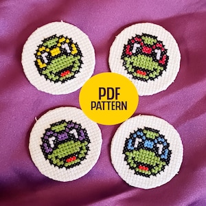May include: Four white, circular cross-stitch patterns featuring Teenage Mutant Ninja Turtle faces, each with a different colored mask: yellow, red, purple, and blue. A yellow circle with "PDF PATTERN" is in the center.