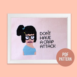 Puede incluir: Un patrón de punto de cruz con un personaje de dibujos animados con cabello negro, gafas y una camisa azul. El texto "Don't have a crap attack" está escrito debajo del personaje. El patrón está disponible para descargar en PDF.