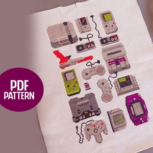 Puede incluir: Patrón de punto de cruz con imágenes pixeladas de consolas de videojuegos retro, mandos y dispositivos portátiles en varios colores. El diseño incluye una nave espacial roja y el texto "PDF PATTERN" en un círculo morado.