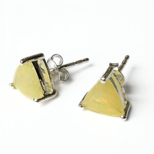 May include: A pair of stud earrings featuring triangular, pale yellow gemstones set in silver-colored metal. The earrings have a post and butterfly backing. The gemstones have a translucent quality, and the setting has a simple, modern design.