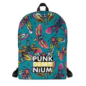 May include: A teal blue backpack with a colorful pattern of skulls and butterflies. The backpack has a black zipper and a yellow and black logo that says "PUNK DEMONIUM".