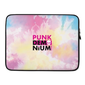 May include: A laptop sleeve with a tie-dye pattern in shades of pink, yellow, and blue. The text "PUNK DEM NIUM" is printed in black with a pink skull and crown graphic.