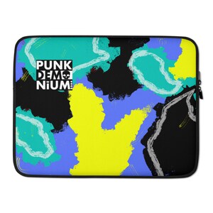 May include: A laptop sleeve with a colorful abstract design featuring black, yellow, blue, and green paint strokes. The text "PUNK DEMONIUM" is printed in white on a black rectangle in the upper left corner.