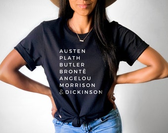 Może przedstawiać: Czarny T-shirt z białym tekstem, który brzmi "Austen, Plath, Butler, Brontë, Angelou, Morrison & Dickinson".