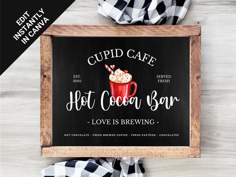 May include: A black chalkboard sign with white text that reads "Cupid Cafe Est. 2005 Served Fresh Hot Cocoa Bar - Love is Brewing - Hot Chocolate Fresh Brewed Coffee Fresh Pastries Chocolates". The sign has a wooden frame and a watercolor illustration of a red mug of hot cocoa with whipped cream, sprinkles, and a candy cane.