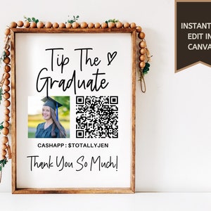 May include: A white sign with a brown wood frame and a black and white image of a graduate. The sign says "Tip The Graduate" with a heart symbol, a QR code, and the text "CASHAPP: $TOTALLYJEN" and "Thank You So Much!"