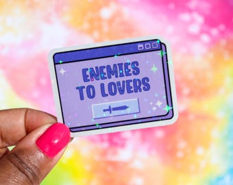 May include: A purple and blue sticker with a computer window design. The window says "Enemies to Lovers" and has a sword icon. The sticker has a glittery finish.