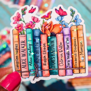 May include: A sticker featuring a stack of books with floral accents and glitter. The books have the names of authors printed on their spines, including Langston Hughes, Alice Walker, Alex Haley, Maya Angelou, Ralph Ellison, James Baldwin, Octavia Butler, Zora Neale Hurston, Frederick Douglass, and Toni Morrison.