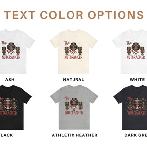 May include: Six t-shirt mockups showing different color options for a t-shirt design. The design features a cartoon illustration of a family of four dressed as nutcrackers. The text on the shirt reads "The Nutcracker". The color options are: Ash, Natural, White, Black, Athletic Heather, and Dark Grey.