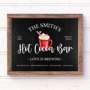 May include: A black chalkboard sign with a wooden frame, advertising "The Smith's Hot Cocoa Bar" with the text "EST. 2005" and "SERVED FRESH". The sign features a watercolor illustration of a red mug of hot cocoa topped with whipped cream, sprinkles, and a candy cane.