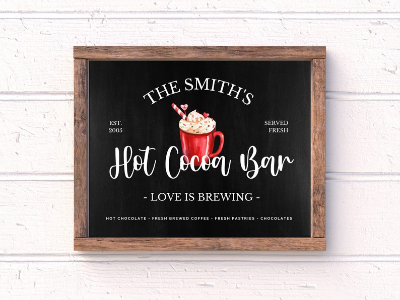 May include: A black chalkboard sign with a wooden frame, advertising "The Smith's Hot Cocoa Bar" with the text "EST. 2005" and "SERVED FRESH". The sign features a watercolor illustration of a red mug of hot cocoa topped with whipped cream, sprinkles, and a candy cane.