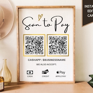 May include: A white sign with a gold frame and the text "Scan to Pay" in black cursive writing. Two black and white QR codes are displayed with gold frames. The text "CASHAPP: $BUSINESSNAME" is below the QR codes. The sign also includes icons for cash, credit, and Apple Pay.