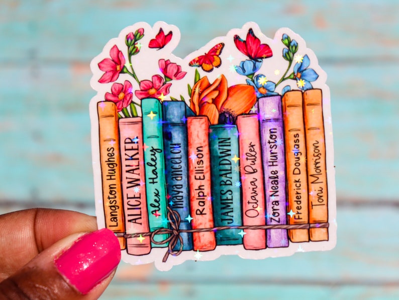 May include: A sticker featuring a stack of books with the names of famous authors, including Langston Hughes, Alice Walker, Alex Haley, Maya Angelou, Ralph Ellison, James Baldwin, Octavia Butler, Zora Neale Hurston, Frederick Douglass, and Toni Morrison. The books are decorated with colorful flowers and butterflies.